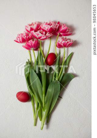 Beautiful terry tulips of pink color with Easter eggs on a white background Beautiful terry tulips of pink color with Easter eggs on a white background 98845653
