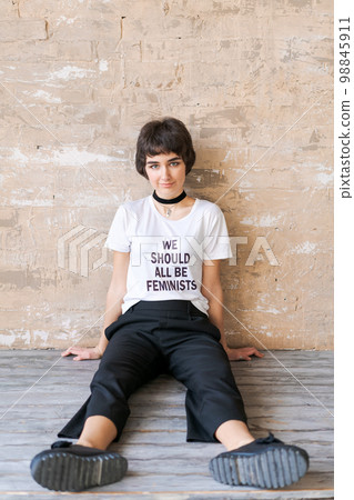 Beautiful smiling girl with short haircut on background wall. Sitting in white 98845911