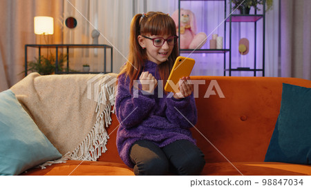 Lovely teen girl at home use smartphone typing browsing, wow yes found out great big win celebrate 98847034