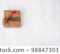 Gift box of craft paper with hearts on the white wooden background. Valentine's Day. 98847303