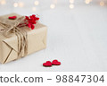 Valentine's Day gift box of craft paper with hearts and red flowers on the white wooden background. 98847304