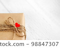 Gift box of craft paper with hearts on the white wooden background. Valentine's Day. 98847307