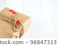 Gift box of craft paper with hearts on the white wooden background. Valentine's Day. 98847313