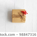 Gift box of craft paper with red flowers on the white wooden background. Valentine's Day. Happy birthday. 98847316