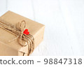 Gift box of craft paper with hearts on the white wooden background. Valentine's Day. 98847318