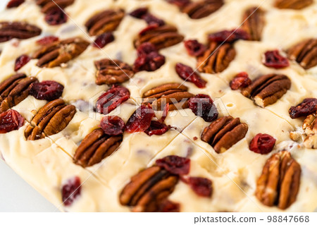 Scoring white chocolate cranberry pecan fudge for cutting into small pieces. Scoring white chocolate cranberry pecan fudge for cutting into small pieces. 98847668