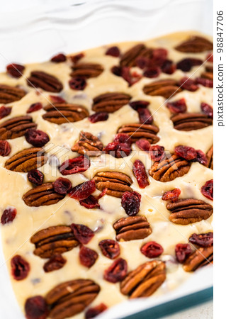 Pouring fudge mixture into the baking pan lined with parchment paper to prepare white chocolate cranberry pecan fudge. 98847706
