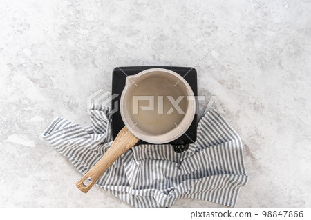 Flat lay. Cooking simple syrup in a small cooking pot. Flat lay. Cooking simple syrup in a small cooking pot. 98847866