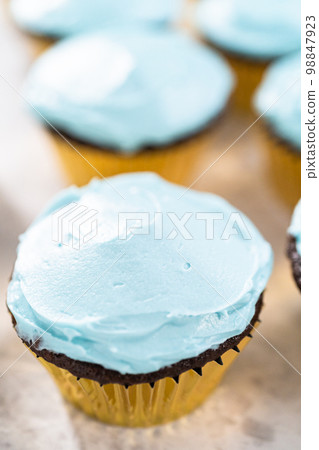 Decorating chocolate cupcakes with buttercream frosting and rainbow candy. Decorating chocolate cupcakes with buttercream frosting and rainbow candy. 98847923