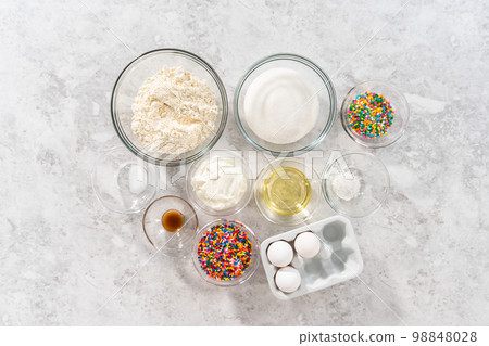 Flat lay. Ingredients in glass mixing bowls to bake funfettti bundt cake. 98848028