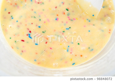 Close up view. Mixing ingredients in a glass mixing bowl to bake funfettti bundt cake. 98848072