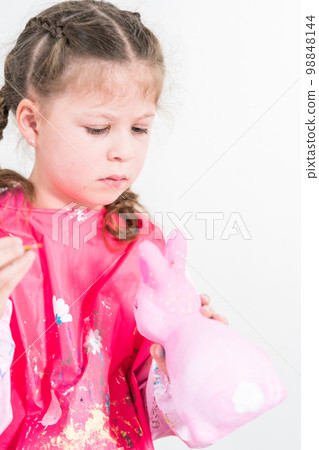 Homeschooling during COVID-19 lockdown. Little girl painting paper mache Easter bunny figurine with acrylic paint. Homeschooling during COVID-19 lockdown. Little girl painting paper mache Easter bunny figurine with acrylic paint. 98848144