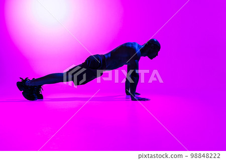 Athlete in plank position does push-ups and arm exercises on studio background Athlete in plank position does push-ups and arm exercises on studio background 98848222