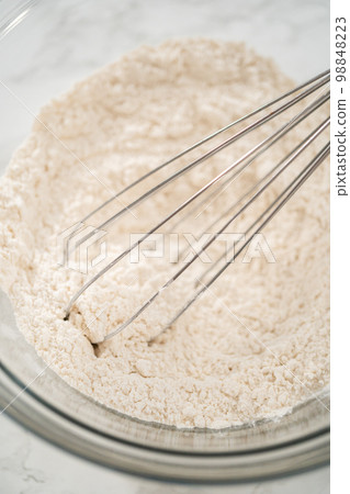Mixing ingredients in a large glass mixing bowl to bake banana oatmeal muffins. Mixing ingredients in a large glass mixing bowl to bake banana oatmeal muffins. 98848223
