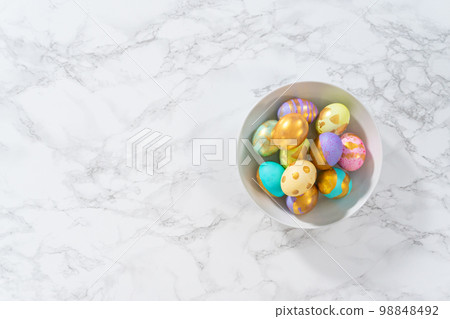Colored and painted with gold hard-boiled eggs on a marble background. 98848492