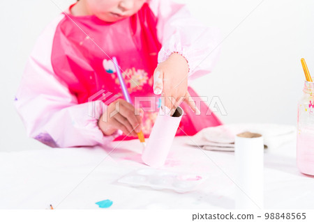 Little girl making a unicorn out of the toilet paper roll and craft paper. Little girl making a unicorn out of the toilet paper roll and craft paper. 98848565