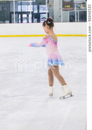 Little girl practicing figure skating on an indoor ice rink. Little girl practicing figure skating on an indoor ice rink. 98848585