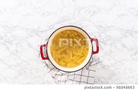 Flat lay. Boiling pasta in an enameled dutch oven to prepare chicken alfredo pasta. Flat lay. Boiling pasta in an enameled dutch oven to prepare chicken alfredo pasta. 98848663