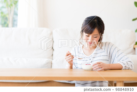 Young woman eating yogurt Young woman eating yogurt 98848910