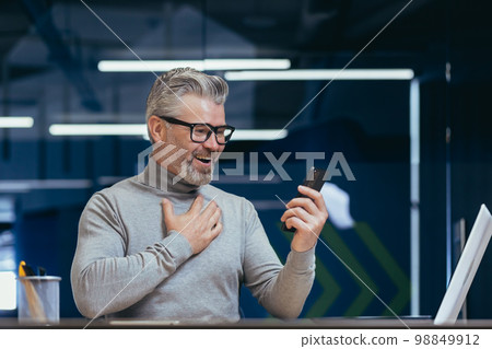 Mature businessman with beard using app on phone inside office, man received online message notification about good news, boss texting online at workplace. 98849912