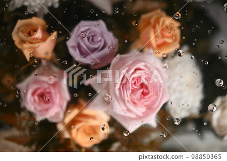 Bouquet of pink and orange roses under transparent blurred foggy glass. Textiles, paper and floral botanical wallpaper Bouquet of pink and orange roses under transparent blurred foggy glass. Textiles, paper and floral botanical wallpaper 98850365