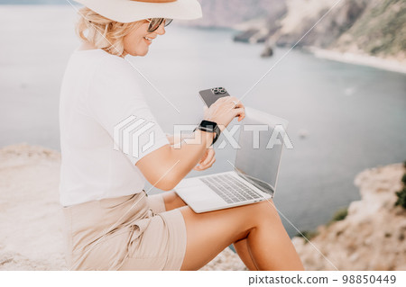 Digital nomad, Business woman working on laptop by the sea. Pretty lady typing on computer by the sea at sunset, makes a business transaction online from a distance. Freelance, remote work on vacation Digital nomad, Business woman working on laptop by the sea. Pretty lady typing on computer by the sea at sunset, makes a business transaction online from a distance. Freelance, remote work on vacation 98850449