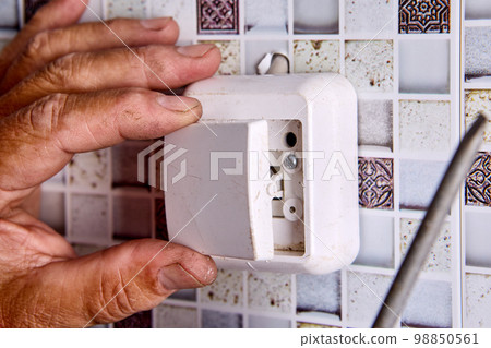 Repair of wall light switch at home. 98850561