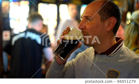 Guy in a pub drinks a beer Guy in a pub drinks a beer 98851279