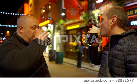 Guys drinking a beer in the Temple Bar district of Dublin by night - travel photography 98851577