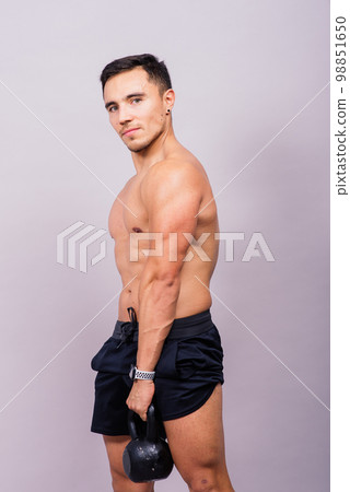 Sporty man working out with a kettlebell. Photo of man on dark background. Strength and motivation Sporty man working out with a kettlebell. Photo of man on dark background. Strength and motivation 98851650