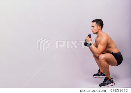 Sporty man working out with a kettlebell. Photo of man on dark background. Strength and motivation Sporty man working out with a kettlebell. Photo of man on dark background. Strength and motivation 98851652