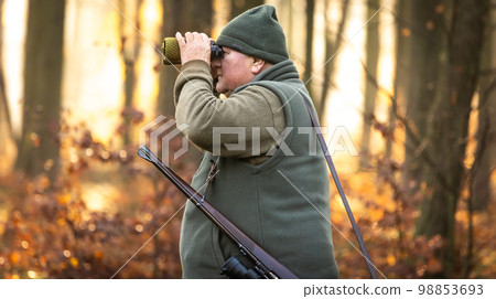 Autumn hunting season, hunter with rifle looking out for some wild animal in a wood or forest, outdoor sports concept 98853693