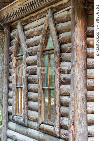Old log cabin with lancet windows in a public park close-up view 98856861