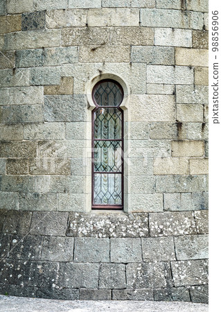 Old medieval window surrounded by stone wall in castle attracts tourists attention. Historical exterior illuminated by bright sunlight 98856906