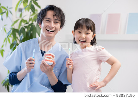 Girl receiving tooth brushing instruction from a dentist 98857190