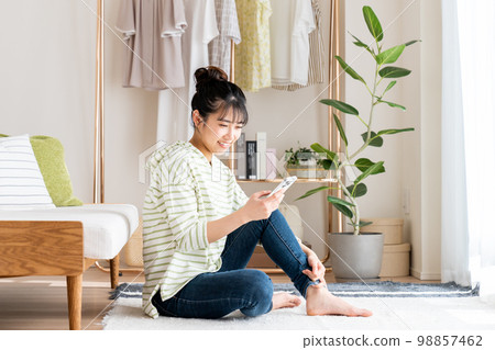 Young woman looking at her smartphone in the living room 98857462