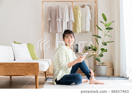 Young woman looking at her smartphone in the living room 98857463