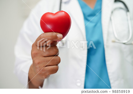Asian woman doctor holding red heart for health in hospital. Asian woman doctor holding red heart for health in hospital. 98858919