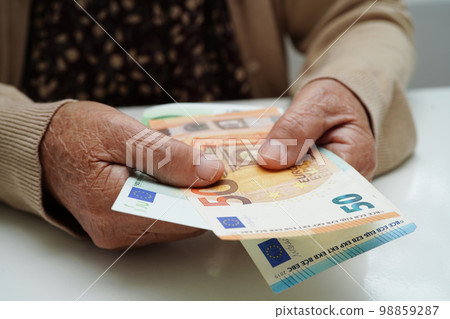 Retired elderly woman holding Euro banknotes money and worry about monthly expenses and treatment fee payment. 98859287