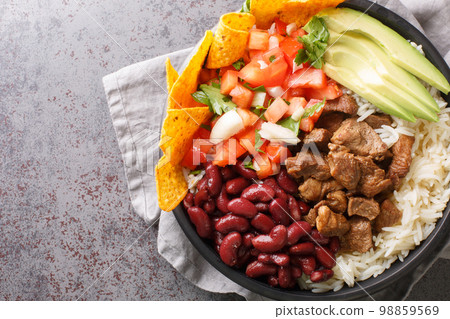 Chifrijo is a delicious traditional Costa Rican dish made with red beans and pork, accompanied by pico de gallo and rice closeup on the plate. Horizontal top view Chifrijo is a delicious traditional Costa Rican dish made with red beans and pork, accompanied by pico de gallo and rice closeup on the plate. Horizontal top view 98859569