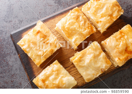 Greek custard pie Galaktoboureko with semolina cream closeup on the wooden board. Horizontal top view 98859590