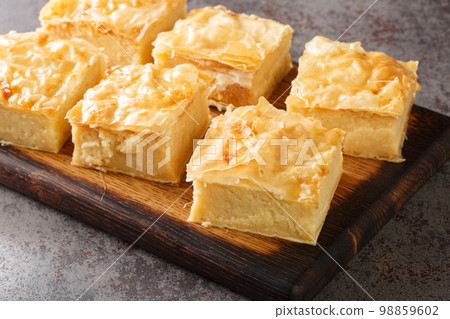 Homemade sweet pastry galaktoboureko with semolina cream closeup on the wooden board. Horizontal Homemade sweet pastry galaktoboureko with semolina cream closeup on the wooden board. Horizontal 98859602