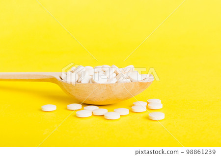 Heap of white pills on colored background. Tablets scattered on a table. Pile of red soft gelatin capsule. Vitamins and dietary supplements concept Heap of white pills on colored background. Tablets scattered on a table. Pile of red soft gelatin capsule. Vitamins and dietary supplements concept 98861239