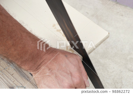 Man cutting through wooden board with hand saw in garden 98862272