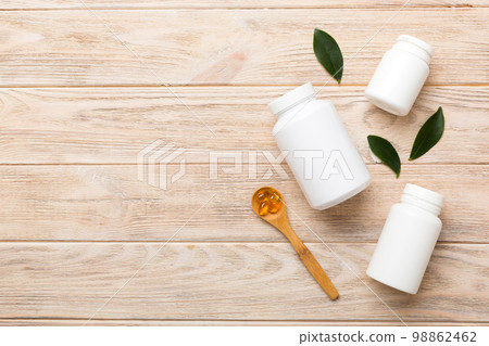 Omega-3 capsules lie in white bottle on a table with green leaves background. Fish oil tablets. Biologically active additives. omega 6, omega 9, vitamin A, E, D, vitamin D3 top view with copy space Omega-3 capsules lie in white bottle on a table with green leaves background. Fish oil tablets. Biologically active additives. omega 6, omega 9, vitamin A, E, D, vitamin D3 top view with copy space 98862462