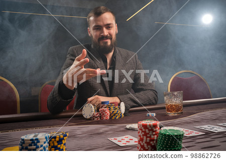 Handsome bearded man is playing poker sitting at the table in casino. Handsome bearded man is playing poker sitting at the table in casino. 98862726