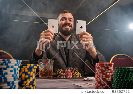Handsome bearded man is playing poker sitting at the table in casino. 98862731