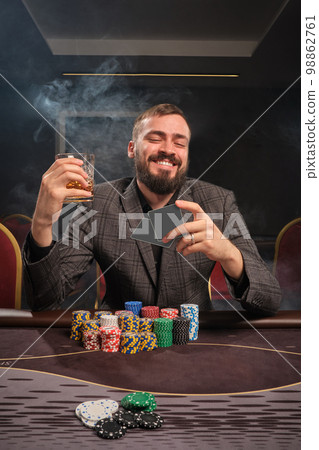 Handsome bearded man is playing poker sitting at the table in casino. 98862761