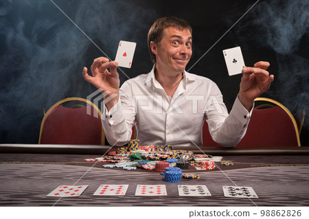 Handsome emotional man is playing poker sitting at the table in casino. Handsome emotional man is playing poker sitting at the table in casino. 98862826
