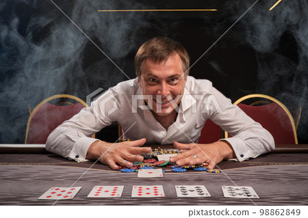 Handsome emotional man is playing poker sitting at the table in casino. Handsome emotional man is playing poker sitting at the table in casino. 98862849